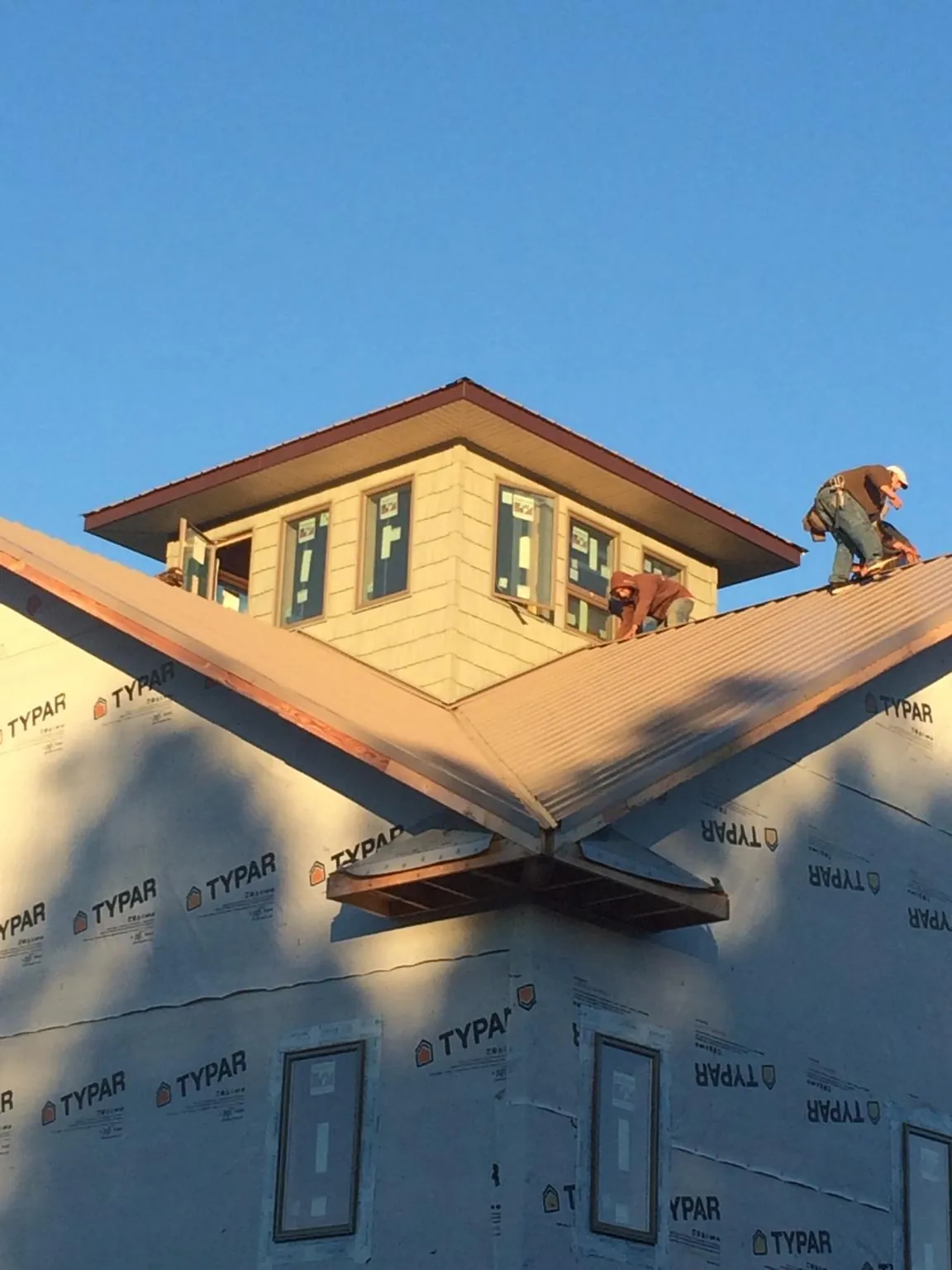 Roofers working around a rooftop cupola on a new metal roof at sunset — Roof Waterproofing in Holland by Roofing Brothers